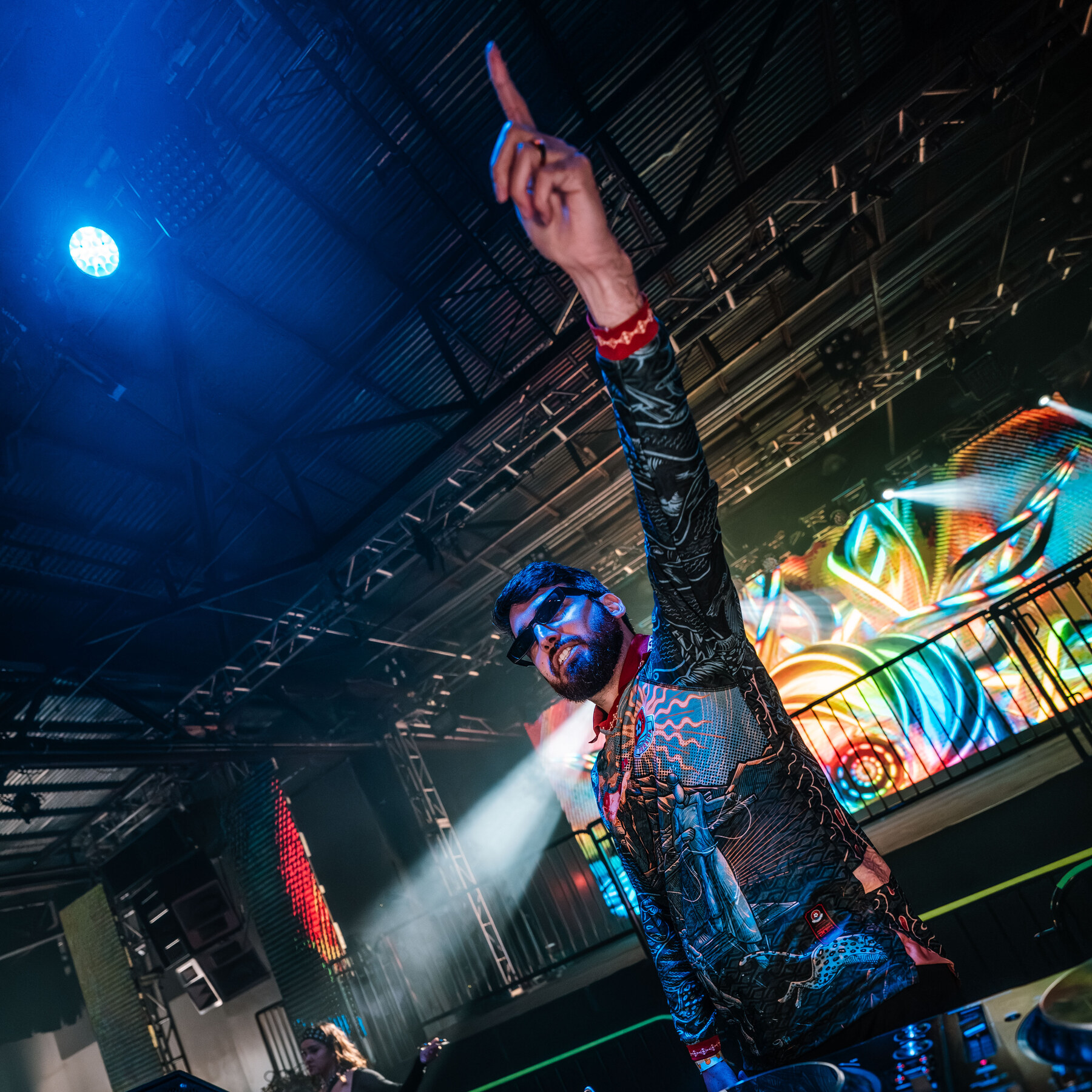 SGRKANE performing behind the DJ booth with one arm raised